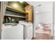 Bright laundry room with washer, dryer, storage shelves, and an adjacent sitting area with natural light at 3700 Miller St, Wheat Ridge, CO 80033