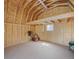 Unfinished barn interior featuring open beam ceiling, plywood walls, concrete floor, and window for natural lighting at 5584 Turnbury Cir, Elizabeth, CO 80107