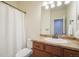 Bathroom with a wooden vanity with a granite countertop, a toilet, a shower curtain, and a large mirror at 5584 Turnbury Cir, Elizabeth, CO 80107