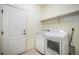 Bright laundry room featuring a modern washer and dryer, white door, and convenient shelving for storage at 5584 Turnbury Cir, Elizabeth, CO 80107