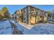 Exterior view of condo with stone facade and brown siding and a snowy yard at 18105 E Ohio Ave # 102, Aurora, CO 80017