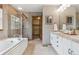 Bright bathroom featuring a soaking tub, step-in shower, and double vanity with white cabinets at 4247 Thistlesage Ct, Castle Rock, CO 80109