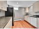 Compact kitchen features white cabinets, black appliances and laminate floors at 6550 E 6Th Avenue Pkwy, Denver, CO 80220