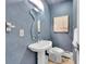 Stylish powder room features blue painted walls, unique mirror, pedestal sink, and modern fixtures at 6550 E 6Th Avenue Pkwy, Denver, CO 80220