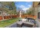 Outdoor seating area features a comfortable lounge set with pillows and a view of the lawn and fence at 107 Prairie Falcon Pkwy, Brighton, CO 80601