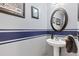 Stylish half bathroom featuring unique painted stripes, framed art, and a pedestal sink at 107 Prairie Falcon Pkwy, Brighton, CO 80601