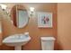 Charming powder room featuring pedestal sink, round mirror, sconces, and painted walls at 14581 E Oberlin Pl, Aurora, CO 80014