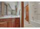 Well-lit bathroom features a wood vanity with a large mirror, and a shower-tub combo with wood storage at 14581 E Oberlin Pl, Aurora, CO 80014