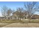 Exterior view of home with mature trees, a large backyard, white fence, and a patio area at 16021 Verbena St, Brighton, CO 80602