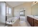 Bright bathroom with a large soaking tub, separate shower, double sink vanity, and views at 16021 Verbena St, Brighton, CO 80602