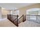 Bright hallway boasts wood railing, neutral walls, and plush carpeting leading to multiple rooms at 16021 Verbena St, Brighton, CO 80602