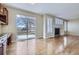 Open concept living room adjacent to kitchen with fireplace, wood floors and sliding glass doors to backyard at 16021 Verbena St, Brighton, CO 80602