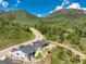 Aerial view of two homes nestled in a lush, green valley with mature trees and a winding road nearby at 5225 Mesa Top Dr, Monument, CO 80132