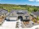 Aerial view of a modern home with a landscaped front yard and long driveway, set against a backdrop of rolling hills at 5225 Mesa Top Dr, Monument, CO 80132