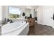 Bright bathroom with large soaking tub under window, and modern vanity and lighting at 5225 Mesa Top Dr, Monument, CO 80132