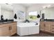 A luxurious bathroom featuring a soaking tub, dual vanities, and plenty of natural light at 5225 Mesa Top Dr, Monument, CO 80132