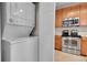 A kitchen with light wood cabinets, stainless steel appliances, and stacked washer and dryer at 3852 S Dallas St # 8-102, Aurora, CO 80014