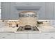 Gas range with white cabinets, tile backsplash, and marble countertops, with stainless appliances at 9715 E 33Rd Ave, Denver, CO 80238
