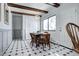Dining area with wooden table and chairs, white walls, beamed ceilings, and black and white tiled floor at 561 Saulsbury St, Lakewood, CO 80226