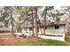 Sprawling ranch style home with a brick patio, mature pine trees, and an attached two car garage at 561 Saulsbury St, Lakewood, CO 80226