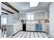 Bright kitchen with skylight, white cabinets, black and white tile flooring, and modern appliances at 561 Saulsbury St, Lakewood, CO 80226