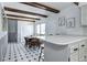 Bright kitchen with dining area, wood beams, white cabinets, and black and white tile flooring at 561 Saulsbury St, Lakewood, CO 80226