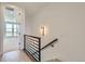 Hallway leading to a sunlit room with sleek metal railing and a sconce at 20588 E 63Rd Ave, Aurora, CO 80019