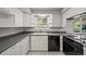 Well-lit kitchen with ample cabinet space, modern black appliances, and a window for natural light at 2704 S Ames Way, Denver, CO 80227