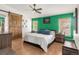 Bedroom featuring a striking accent wall, wood flooring, a ceiling fan, and a barn door to the en suite at 1510 S De Gaulle Cir, Aurora, CO 80018