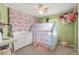 Bedroom with an eye-catching floral accent wall, and a crib with see-through mesh for added safety and visibility at 1510 S De Gaulle Cir, Aurora, CO 80018