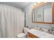 Well-lit bathroom with a wood-trimmed mirror, a toilet, and a bathtub with a shower curtain, complemented by grey walls at 2208 Champlain Dr, Boulder, CO 80301