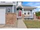 Inviting front porch with brick columns, a white railing, and a bright red front door at 4235 Lark Sparrow St, Highlands Ranch, CO 80126