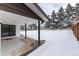 Covered patio and snow-covered backyard with privacy fence and mature trees at 5886 S Logan St, Centennial, CO 80121