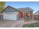 Gray and brick ranch home with a two-car garage and red front door at 7814 Club Crest Dr, Arvada, CO 80005