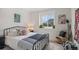 Cozy bedroom with a metal frame bed, colorful pillows, and a large window overlooking the neighborhood at 6027 N Netherland Ct, Aurora, CO 80019