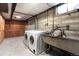 Spacious laundry room featuring a washer, dryer, and sink with concrete flooring and walls at 479 S Kendall St, Lakewood, CO 80226