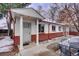The home's entrance featuring classic pillars, red trim, and low brick siding at 4078 Ames St, Wheat Ridge, CO 80212