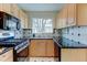 Well-lit kitchen featuring stainless steel appliances, maple cabinets, and black countertops at 4078 Ames St, Wheat Ridge, CO 80212