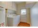 This laundry room features a washer, a dryer, white cabinets, and a door to the outside at 4078 Ames St, Wheat Ridge, CO 80212
