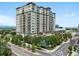 Modern high-rise apartment building with multiple balconies, landscaping, and adjacent city street at 5455 Landmark Pl # 815, Greenwood Village, CO 80111