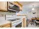 Open kitchen featuring white appliances and light wood cabinetry next to the dining area at 8555 S Fairmount Dr # 107, Denver, CO 80247