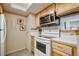 Cozy kitchen with a white range, built-in microwave, and light wood cabinets at 8555 S Fairmount Dr # 107, Denver, CO 80247