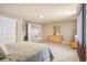 Well-lit bedroom with an open doorway, carpet flooring, and a wooden dresser at 19602 E 63Rd Dr, Aurora, CO 80019