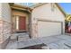 Charming home exterior features a two car garage, stone accents, and a covered entryway to a red front door at 19602 E 63Rd Dr, Aurora, CO 80019