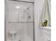 Bright shower features a glass door, tile surround, shower head, and convenient seating inside at 13631 E Marina Dr # 105, Aurora, CO 80014