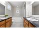 Well-lit bathroom with double sinks, bathtub, shower with glass door, and black and white checkered tile floor at 9134 E 29Th Pl, Denver, CO 80238