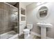 Modern bathroom featuring glass-enclosed shower, toilet, and pedestal sink with a round mirror at 9134 E 29Th Pl, Denver, CO 80238