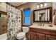 Traditional bathroom with neutral tiling, decorative shower curtain, and framed mirror at 12534 W Hoover Ave, Littleton, CO 80127