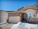 Tan two-story home with stone accents and a two-car garage, nestled in a snowy landscape at 6945 Fargo Trl, Littleton, CO 80125