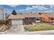 Charming brick home with a two-car garage, manicured lawn, and inviting front entrance with colorful landscaping at 412 N 10Th Ave, Brighton, CO 80601
